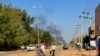 Des personnes déplacées par le conflit au Soudan marchent le long d'une route tandis que de la fumée s'élève au loin lors d'affrontements à Wad Madani, la capitale de l'État d'al-Jazirah, le 16 décembre 2023.