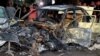 Orang-orang memperhatikan kendaraan yang hangus terbakar di lokasi ledakan bom di luar Masjid Sayeda Zeinab di selatan Kota Damaskus, Ibu Kota Suriah, 27 Juli 2023. (Foto: SANA/handout via Reuters)
