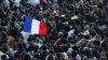 A demonstrator holds a French flag as people gather at the Place de la Republique after partial results in the second round of the early French parliamentary elections, in Paris, July 7, 2024.