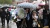 Iranian women walk through rain in a flower market, ahead of Nowruz, the Iranian New Year, in Tehran, March 16, 2023. 