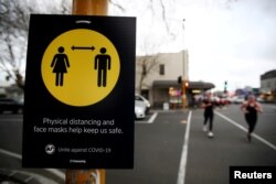 Sejumlah warga Selandia Baru sedang berolahraga sambil melewati papan jaga jarak untuk meredam penyebaran Covid-19 di Auckland, Selandia Baru, 31 Agustus 2020. (Foto: Fiona Goodall/Reuters)