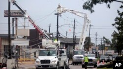 FILE - Utility crews work to restore electricity in Houston, July 11, 2024.