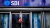 Seorang pria memeriksa ponselnya di depan cabang State Bank of India (SBI) di Kolkata, India, 9 Februari 2018. (Foto: REUTERS/Rupak De Chowdhuri)