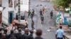 Des gens retirent un débris de la route alors que des soldats comoriens patrouillent à la suite d'une manifestation de l'opposition à Moroni le 17 janvier 2024, suite à l'annonce des élections présidentielles.