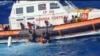 Foto selebaran ini diambil pada 5 Agustus 2023 oleh Penjaga Pantai Italia, dirilis 6 Agustus 2023, menunjukkan penyelamat membantu migran naik perahu penyelamat selama operasi di selatan Lampedusa. (Penjaga Pantai Italia / Guardia Costiera / AFP)