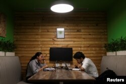 Dua orang tengah menggunakan laptop mereka di kantor Deloitte di Gurugram, India, 13 Juni 2023. (REUTERS/Anushree Fadnavis)