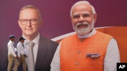 ভারতের আহমেদাবাদে অস্ট্রেলিয়ার প্রধানমন্ত্রী অ্যান্থনি অ্যালবানিজ এবং ভারতের প্রধানমন্ত্রী নরেন্দ্র মোদির একটি ছবির পাশ দিয়ে পুলিশ সদস্যরা হেঁটে যাচ্ছেন। ৮ মার্চ, ২০২৩।