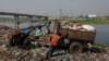 FILE - Workers dump waste into a landfill beside Dhaleshwari River, which flows into the Buriganga River, in Savar, near Dhaka, Bangladesh, March 7, 2023. 