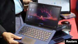 Seorang pria memegang laptop produksi Reliance yang akan segera diluncurkan dengan nama pasar "JioBook", di kios Jio pada acara "India Mobile Congress 2022" di Pragati Maidan, New Delhi, India, 3 Oktober 2022. (REUTERS/Anushree Fadnavis)