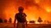 Grant Douglas pauses while evacuating as the Park Fire jumps Highway 36 near Paynes Creek in Tehama County, California, July 26, 2024. The fire is the largest blaze in California this year.