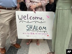A family member holds up a "Welcome" sign as they meet Shalom Korai for the first time in North Charleston, South Carolina, July 10, 2024. At the bottom of the sign is a message in capital letters that says "WE ARE SO GLAD TO HAVE FOUND YOU!"