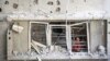 A Palestinian child looks out of the window of a building damaged in an Israeli strike on the Nuseirat refugee camp in the central Gaza Strip, July 6, 2024. 