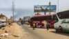 People wait next to passenger buses as smoke billows in an area in Khartoum where fighting continues between Sudan's army and paramilitary forces, April 28, 2023.