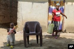 Linda Kabugho, 23, with her 1-year-old daughter, walks near their home in Bundibugyo district, Western Uganda, June 30, 2024.