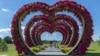 A woman swings from a heart-shaped flower installation in Dobro Park, Motyzhyn, Kyiv region, Ukraine, June 26, 2024. Despite hardships brought by war flowers fill Kyiv and other Ukrainian cities. 