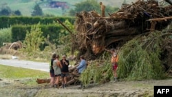 FILE - People stand next to debris in a flood-affected area in the aftermath of Cyclone Gabrielle near Napier, New Zealand, Feb. 16, 2023.