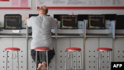 Seoranginvestor tampak mengamati layar yang menampilkan pergerakan nilai saham di sebuah perusahaan sekuritas di Fuyang, provinsi Anhui, China, pada 29 Mei 2023. (Foto: AFP)