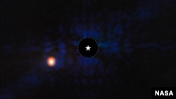 The exoplanet Epsilon Indi Ab is seen with NASA’s Webb Space Telescope’s MIRI (Mid-Infrared Instrument). A star symbol marks the host star Epsilon Indi A, whose light has been blocked by a coronagraph, resulting in the dark circle marked with a dashed white line. 