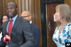 FILE - St. Louis Circuit Attorney Gabe Gore, left, speaks at a news conference, July 23, 2024, in St. Louis, after a judge overturned the murder conviction of Christopher Dunn. At right is Dunn’s wife, Kira.