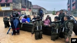 In this photo released by Malaysia's National Disaster Management Agency, members of the army evacuate residents of Chaah town in Segamat, southern Johor state, Malaysia, March 1, 2023.