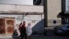 People walk by a graffiti reading 'No surrender! KM (Kosovska Mitrovica) remains!' near a polling station in the north of Mitrovica, predominantly populated by the ethnic Serb minority during the municipal elections in the north of Kosovo, Apr. 23, 2023. 
