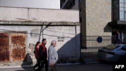 People walk by a graffiti reading 'No surrender! KM (Kosovska Mitrovica) remains!' near a polling station in the north of Mitrovica, predominantly populated by the ethnic Serb minority during the municipal elections in the north of Kosovo, Apr. 23, 2023. 
