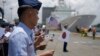 Anggota Penjaga Pantai Filipina mengibarkan bendera kecil Filipina, AS dan Jepang dalam upacara penyambutan kapal penjaga pantai AS dan Jepang di dermaga Manila, Filipina, Kamis, 1 Juni 2023. (AP/Aaron Favila)