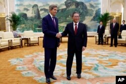 Utusan Khusus Presiden AS untuk Iklim John Kerry, kiri, dan Perdana Menteri China Li Qiang berjabat tangan sebelum pertemuan di Aula Besar Rakyat di Beijing, 18 Juli 2023. (Foto: via AP)