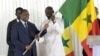 Le capitaine sénégalais Kalidou Koulibaly (à droite) reçoit le drapeau national sénégalais des mains du président sénégalais Macky Sall (à gauche), à Dakar, le 9 janvier 2024, avant le départ de l'équipe pour la Côte d'Ivoire. (Photo Seyllou / AFP)