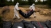 Members of a forensic team carry a plastic bag with a body inside as they work in an exhumation in a mass grave in Lyman, Ukraine, Oct. 11, 2022. 