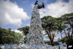 Sebuah patung seni raksasa menunjukkan keran yang menuangkan botol plastik, di markas Program Lingkungan PBB (UNEP) di Nairobi, Kenya, Rabu, 2 Maret, 2022. (Foto: AP)