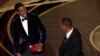 Komedian Chris Rock (kiri) bereaksi setelah aktor Will Smith menamparnya di atas panggung dalam ajang Oscar yang digelar di Los Angeles, California, pada 27 Maret 2022. (Foto: AP/Chriss Pizzello)
