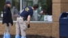 Anggota FBI tampak mengamati lubang pada kaca yang tertembak peluru di lokasi penembakan di supermarket Tops di Buffalo, New York, pada 16 Mei 2022. (Foto: Reuters/Brendan McDermid)