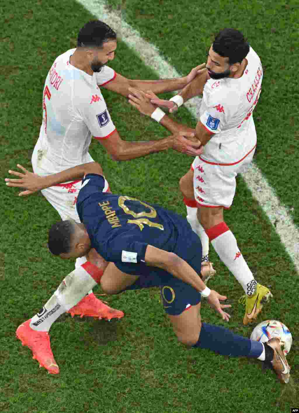 Attaquant ya France #10 Kylian Mbappé azali kowelela ndembo kati na défenseur ya Tunisie #05 NAder Ghandri na milieu ya Tunisie #18 Ghailene Ghaalali na match ya groupe D ya Mondial Qatar 2022 na stade Al-Rayyan, Doha, 30 novembre 2022. (Photo Antonin THU