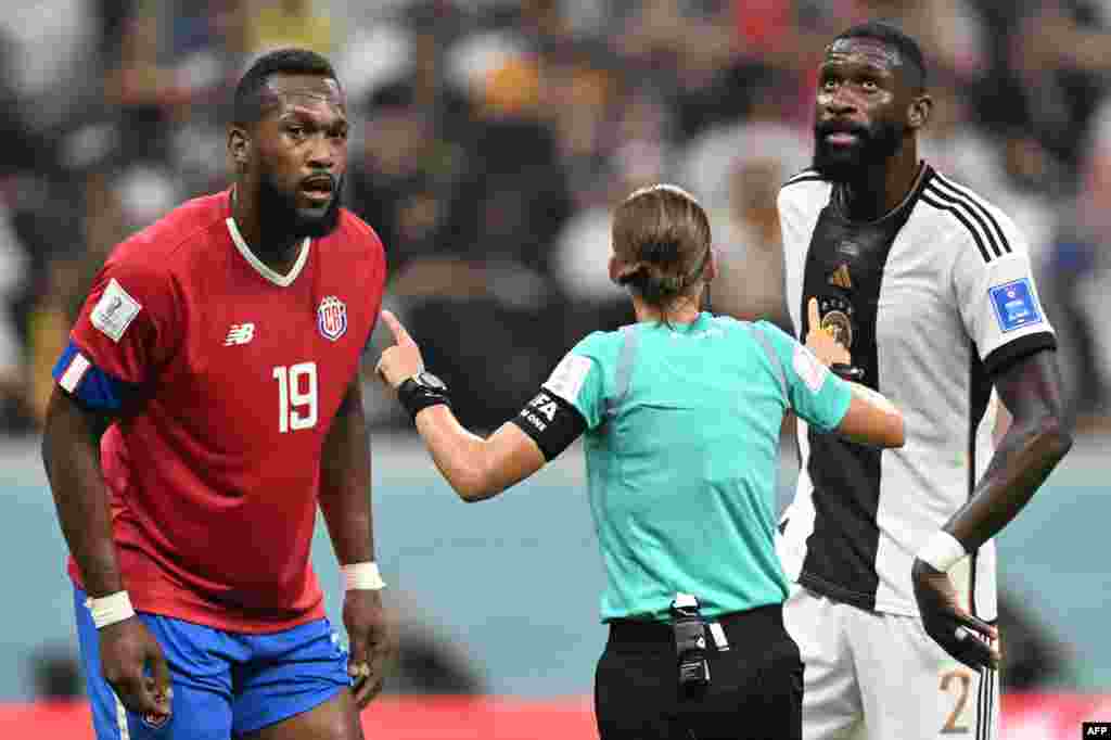 Mobeti piolo ya mwasi ya ekolo France Stephanie Frappart (C) azali koloba na défenseur ya costa Rica #09 Kendal Wastin (G) na défenseur ya Allemagne #02 Antonio Ruediger na match ya Mondial Qatar 2022 na stade Al Khor, Doha, 1er décembre 2022. (Photo Raul