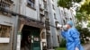 Seorang relawan menggunakan megafon ketika berbicara dengan para warga di sebuah komplek apartemen di Shanghai, China, di tengah lockdown yang diberlakukan di wilayah tersebut, pada 12 April 2022. (Foto: Xinhua via AP/Chen Jianli)