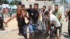 People carry a casualty at the site of what Palestinians say was an Israeli strike at a tent camp in Khan Younis in the southern Gaza Strip, July 13, 2024.