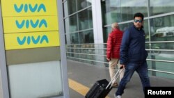 Un hombre camina cerca de un cartel de la aerolínea Viva Air, luego de que la aerolínea cancelara todos sus vuelos debido a las dificultades financieras que enfrenta para operar en el Aeropuerto El Dorado, en Bogotá, Colombia, el 28 de febrero de 2023.