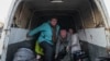 Pengungsi dari Mariupol turun dari mobil van yang mereka gunakan sebagai transportasi setibanya di sebuah pusat pengungsi di Zaporizhia, Ukraina, Jumat, 25 Maret 2022. (AP Photo/Evgeniy Maloletka)