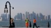 Dengan latar belakang cakrawala kota, para pekerja migran beristirahat di pelabuhan Doha, di Doha, Qatar, Minggu, 13 November 2022. (Foto: AP)