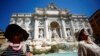 Dua orang perempuan tampak duduk di dekat air mancur Trevi saat cuaca panas saat gelombang panas melanda Eropa di Roma, Italia, 19 Juli 2022. (Foto: Reuters)