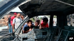 Anak-anak melihat kendaraan yang rusak di lokasi ledakan di kawasan Kota Sadr, Irak, Kamis, 15 April 2021. Polisi Belgia telah menangkap seorang imigran Irak yang diduga menjadi anggota sel Al-Qaida yang melakukan serangan bom mobil di Baghdad antara 2009-2010, (Foto: AP)