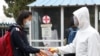 Seorang siswa perempuan yang memakai masker membersihkan tangannya dengan cairan pembersih sebelum memasuki area Sekolah Menengah Pertama Kumsong di Pyongyang, Korea Utara, pada 3 November 2021. (Foto: AP/Cha Song Ho)