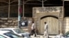FILE - People walk past a banner of the Islamic State in Iraq and the Levant (ISIL) in the city of Mosul, June 28, 2014.