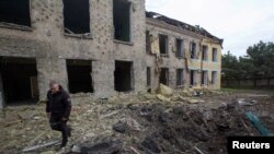 Поліцейський йде біля будівлі школи, пошкодженої російським військовим ударом, під час нападу Росії на Україну, у селищі Костянтинівка Донецької області, Україна, 22 травня 2022 року. Фото зроблено 22 травня 2022 року. REUTERS /Ганна Кудрявцева