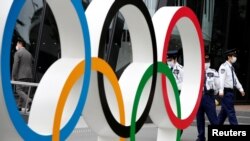 资料照：日本保安在东京日本奥委会总部外看守奥运标识（2021年5月18日）