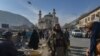 Seornag anggota pasukan Taliban berdiri di samping penjual makanan burung di salah satu pasar di Kabul, pada 3 Desember 2021. (Foto: AFP/Arman Sahel)
