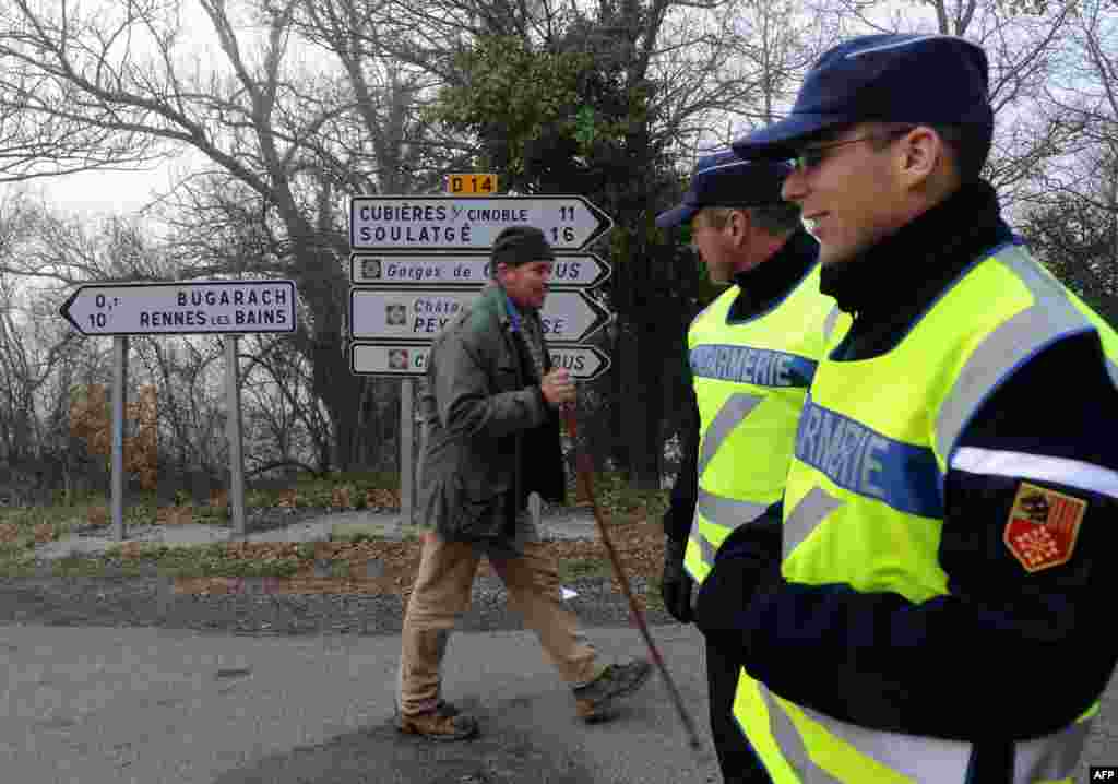 A man walks with a stick past gendarmes controlling access to the French southwestern village of Bugarach, Dec. 20, 2012.
