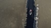 ARCHIVO - Isabel Apaza y Gabriel Flores navegan en su bote por un estrecho sendero de agua cerca de la orilla del lago Titicaca en la temporada de sequía en Huarina, Bolivia, el 3 de agosto de 2023.