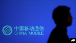 一名男子走过有中国移动标识的广告牌。
